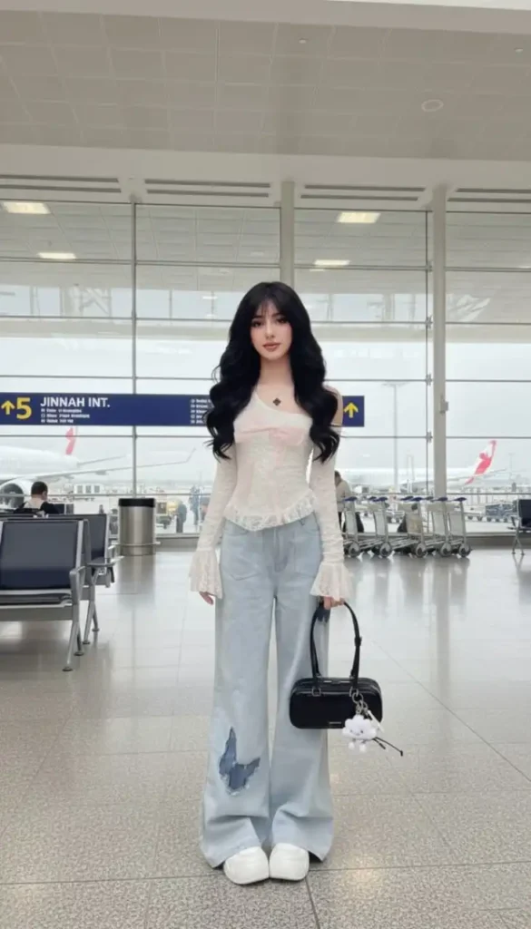 White lace one-shoulder top with a pink bow and butterfly-detail baggy jeans.